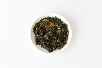 White bowl filled with organic oolong tea leaves on a white background