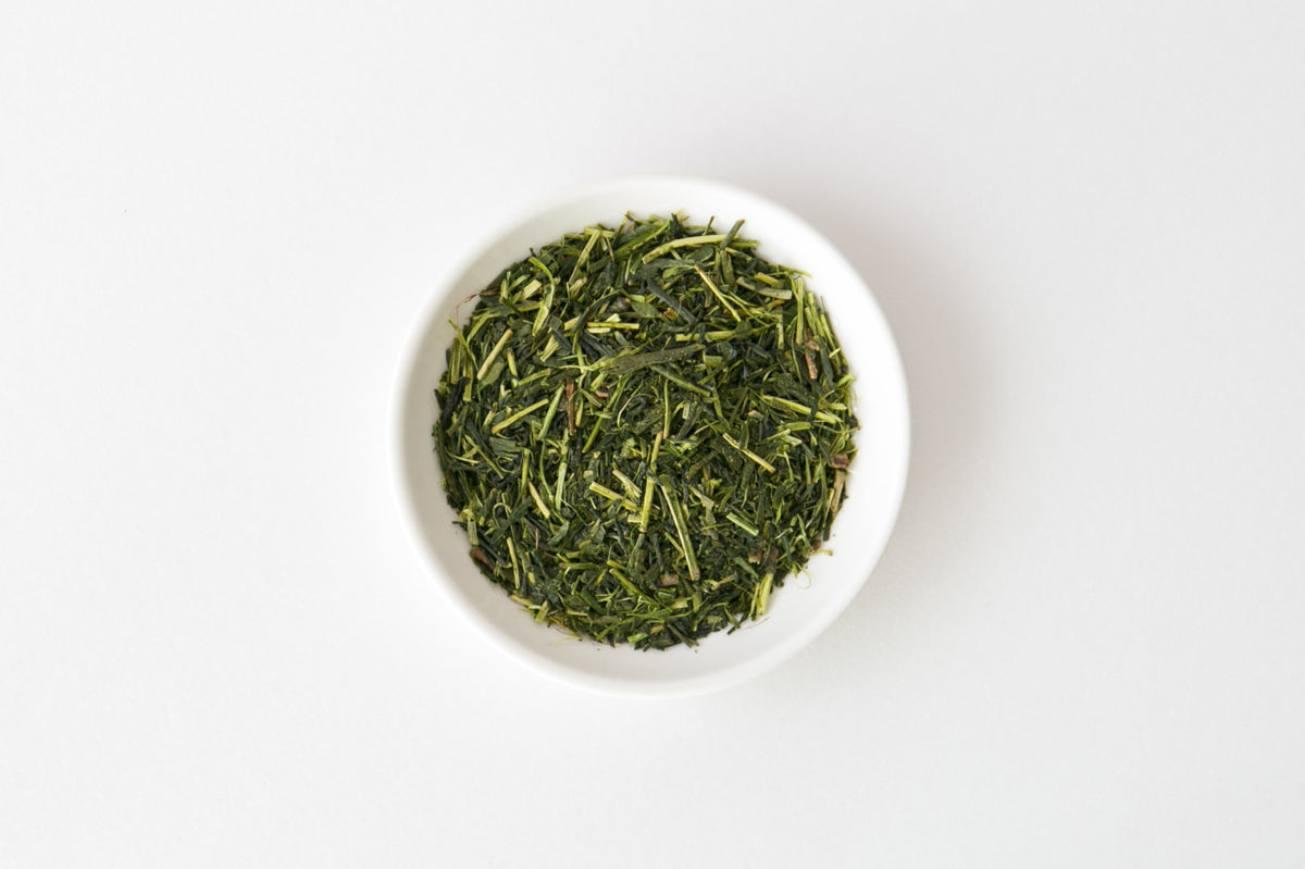 White bowl filled with Shiraore green tea leaves on a white background